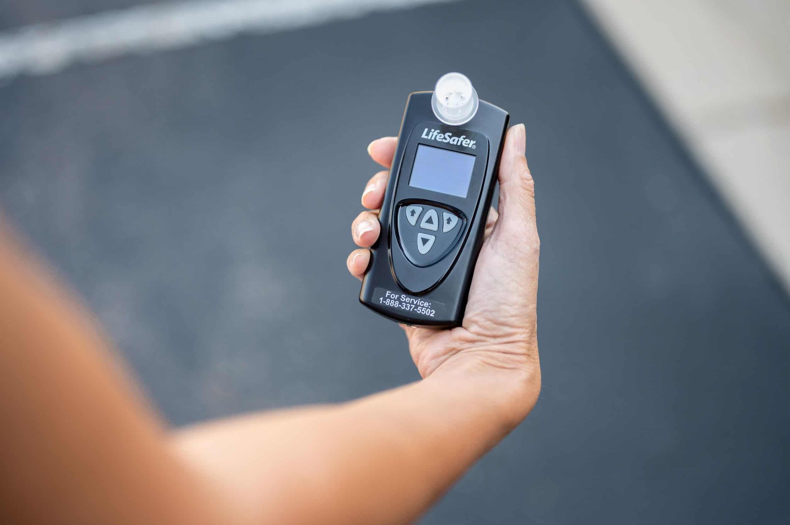 Person holding a LifeSafer ignition interlock device